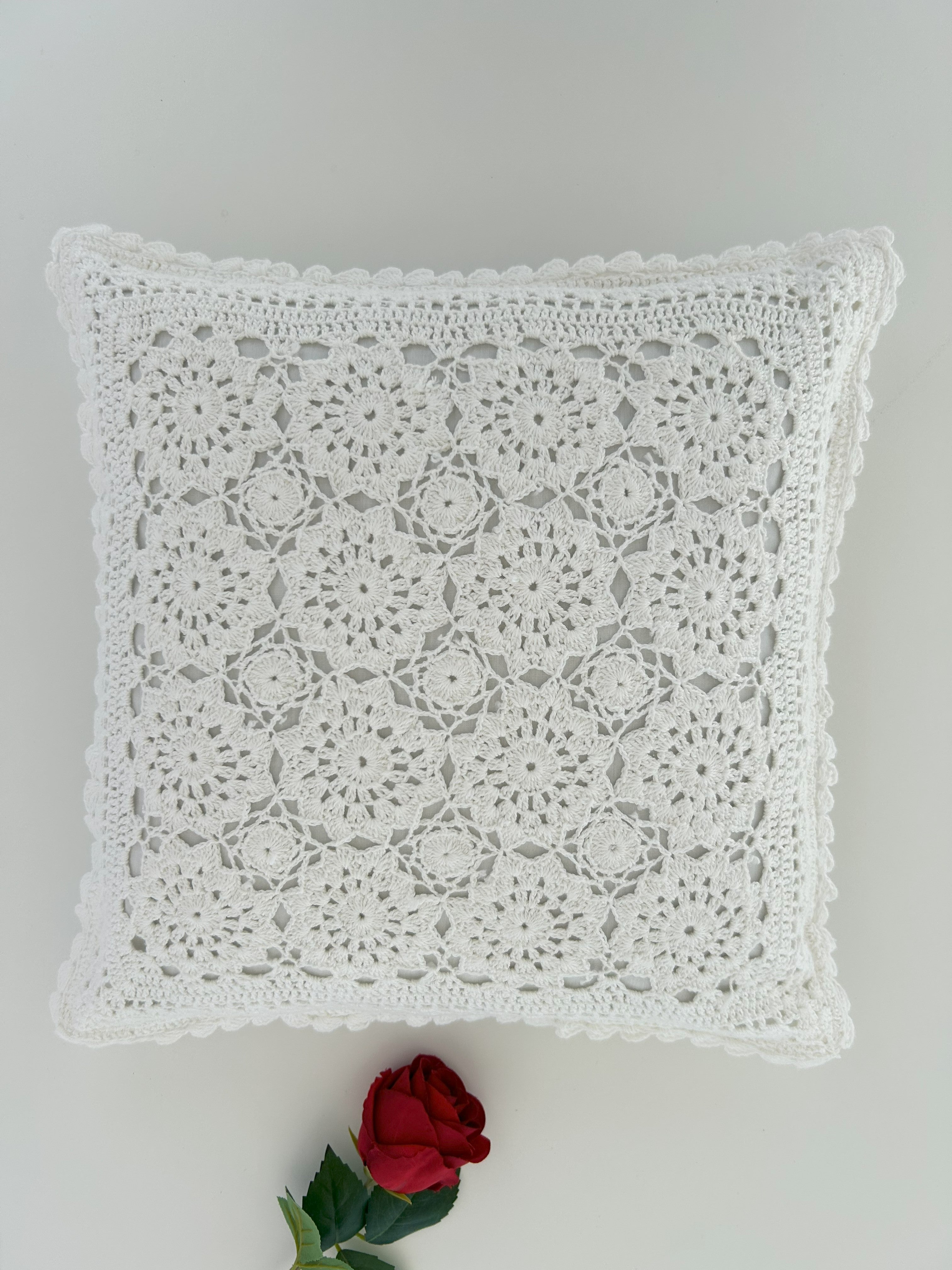 White lace pillow on a gray background with a red rose.