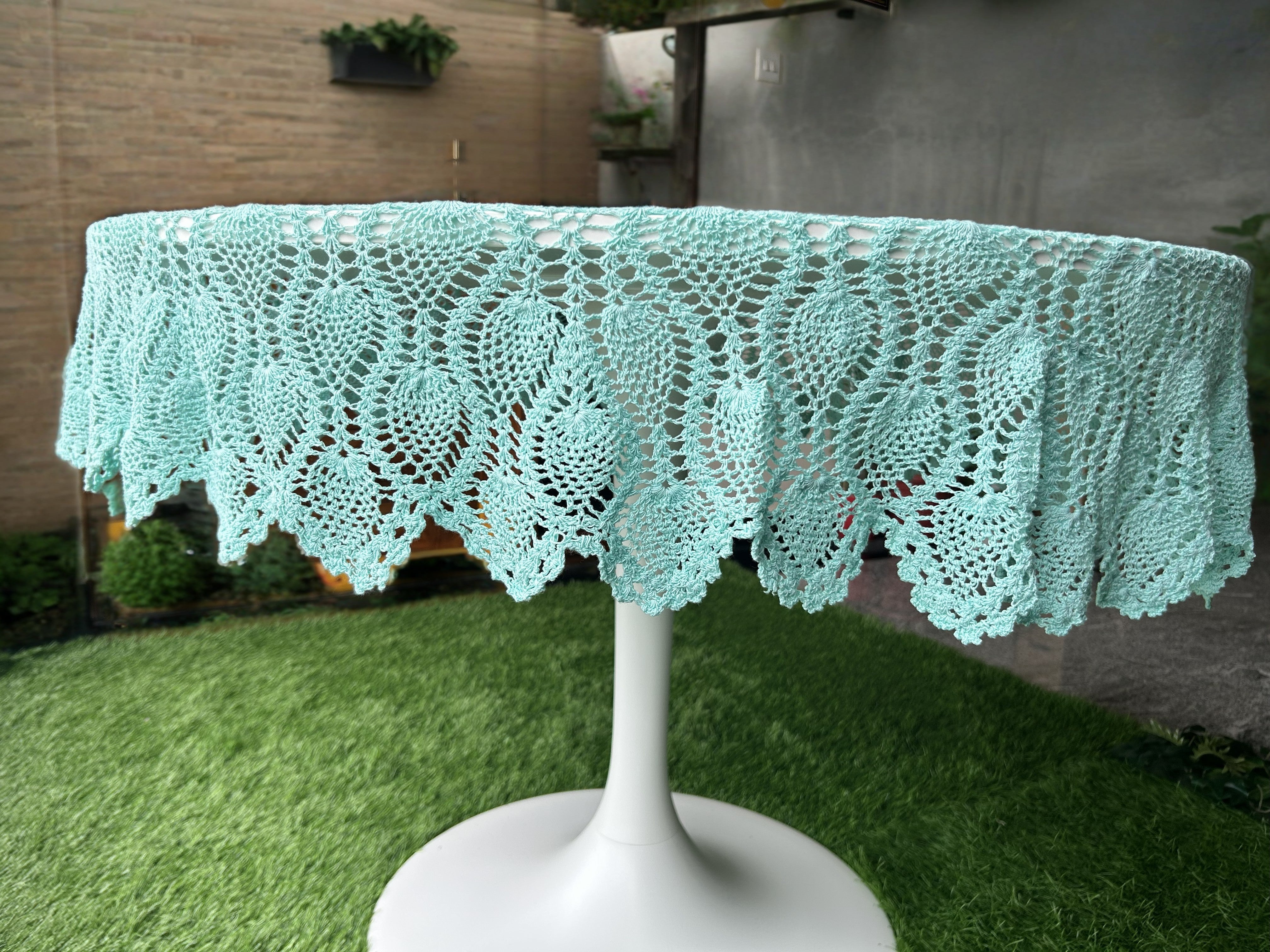 Teal lace tablecloth on a white pedestal table outdoors.