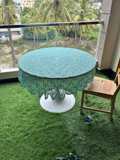 Round table with a green lace tablecloth on a balcony with greenery